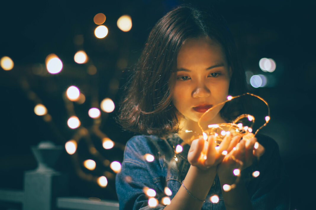 woman-in-blue-shirt-holding-lighted-string-of-lights-1271971-1