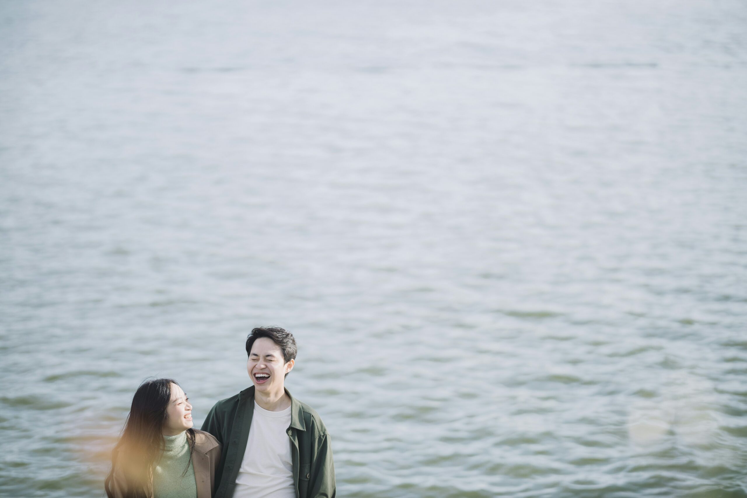 man and woman smiling beside body of water during daytime